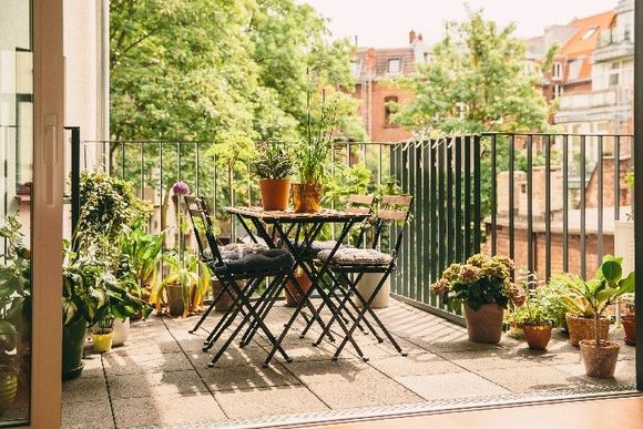 Ein Gartentisch mit Stühlen auf sommerlichem Balkon.
